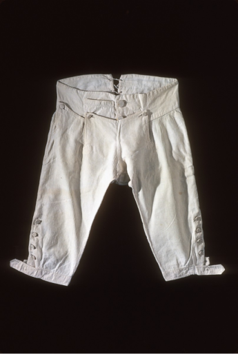 a pair of white cotton and linen knew length Breeches, English or American, 1765-1785. The fabric is known as dimity and has a slight stripe. In the collection of Colonial Williamsburg.