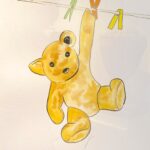 A watercolour painting of a yellow teddy bear hanging by one paw from a washing line with green, orange and yellow pegs. He has black button eyes and nose.