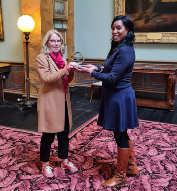 Louise Jackson, Chair of Trustees, receives the glass Young Ealing Foundation award trophy from Chantel Noel of Descendants