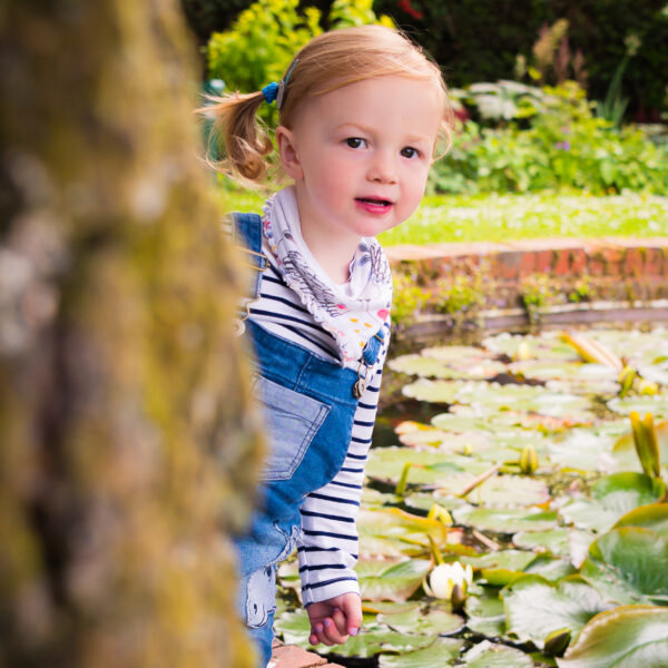 Child hiding behind tree