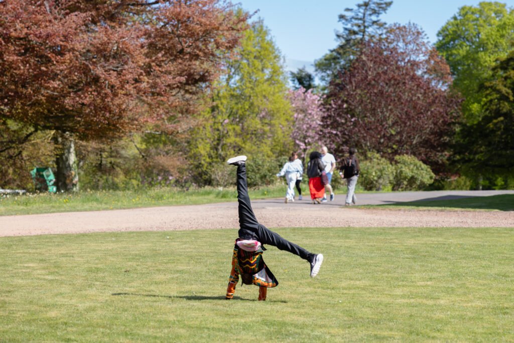 Young person cartwheeling on the front grass circle at Paxton House on a trip