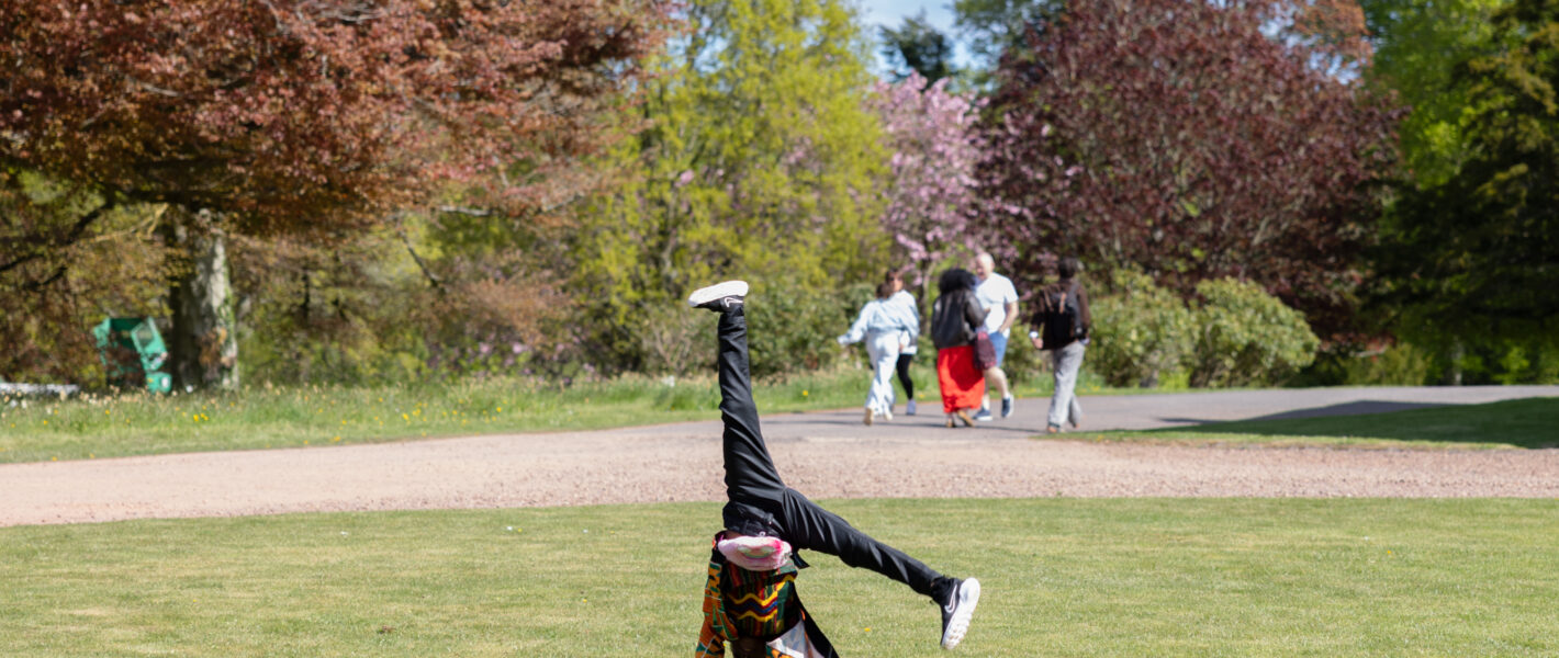 Young person cartwheeling on the front grass circle at Paxton House on a trip