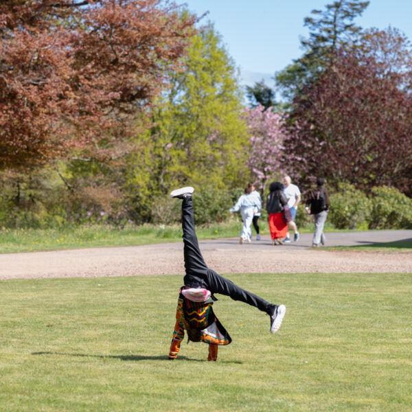 Young person cartwheeling on the front grass circle at Paxton House on a trip