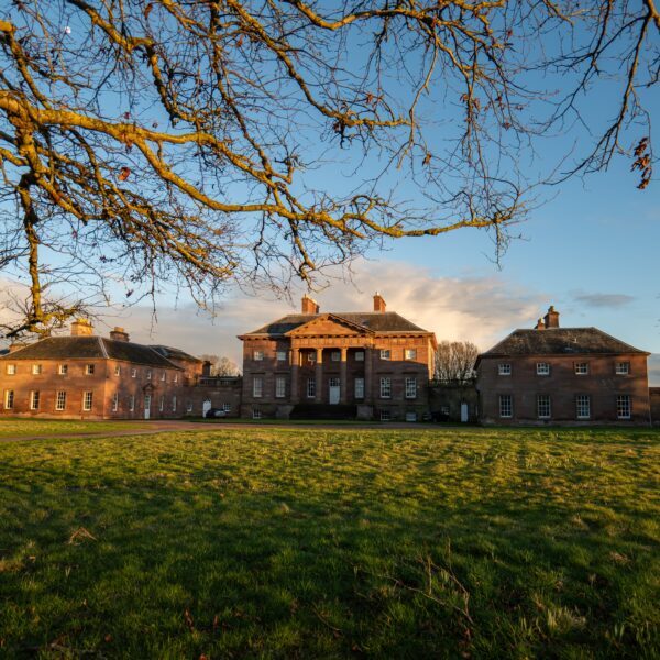 A distant view of Paxton House beneath the branches on an autumnal day