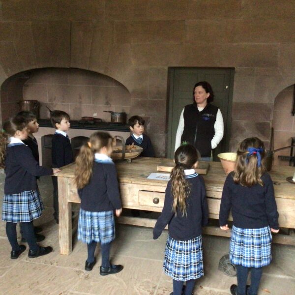 Group of young school children in the old kitchen around the prep table. They are on a school trip to Paxton House