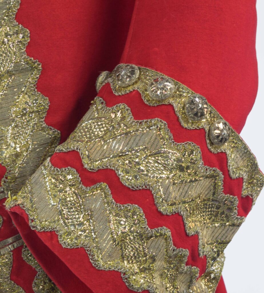 Red coat sleeve close up highlighting gold detailing on the cuffs. Costume collection Paxton House